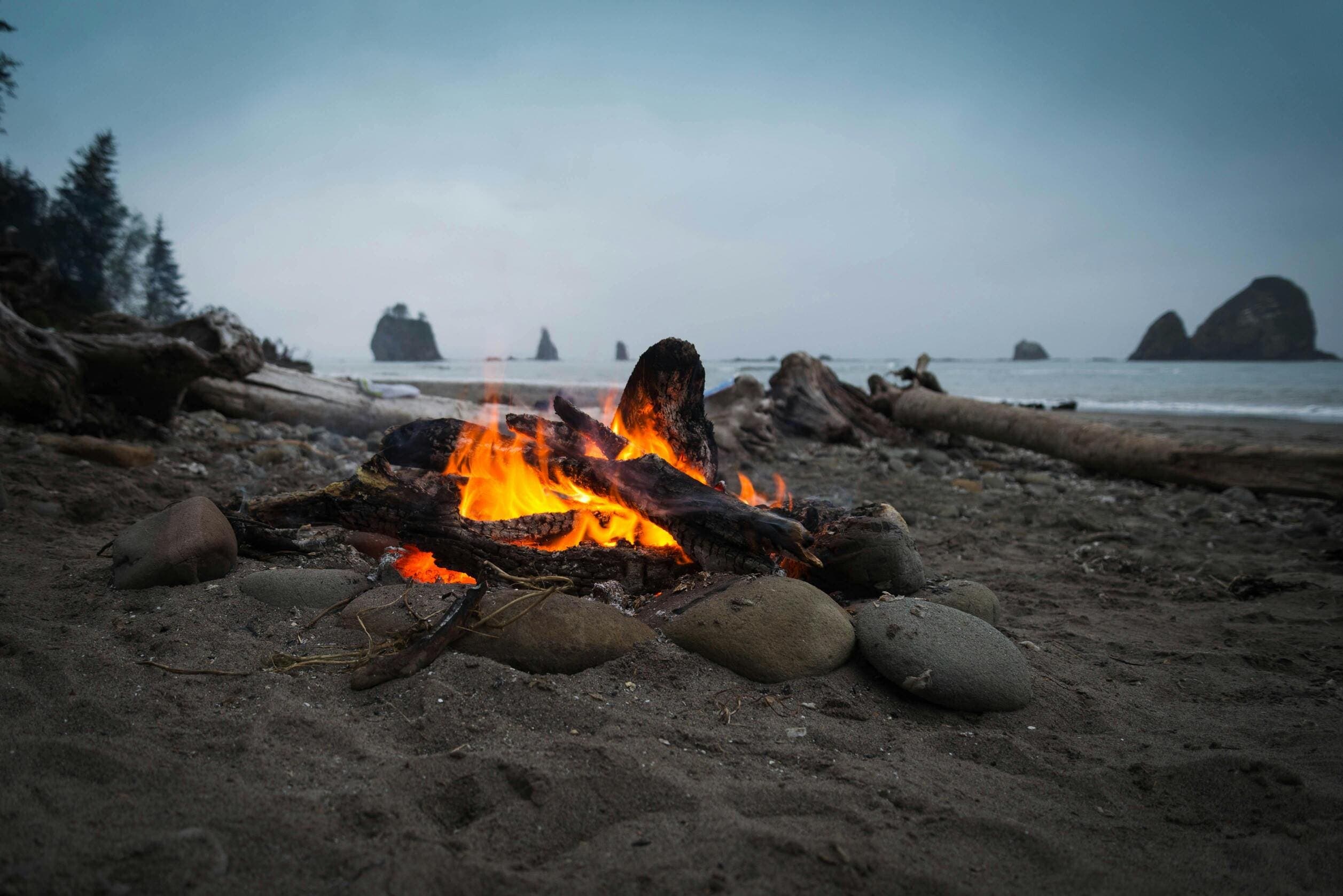 Campfire burns on a rocky, misty beach