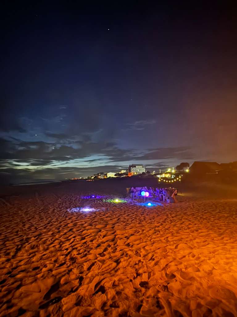 Illumination Experience — glowing orbs and string lights on the beach