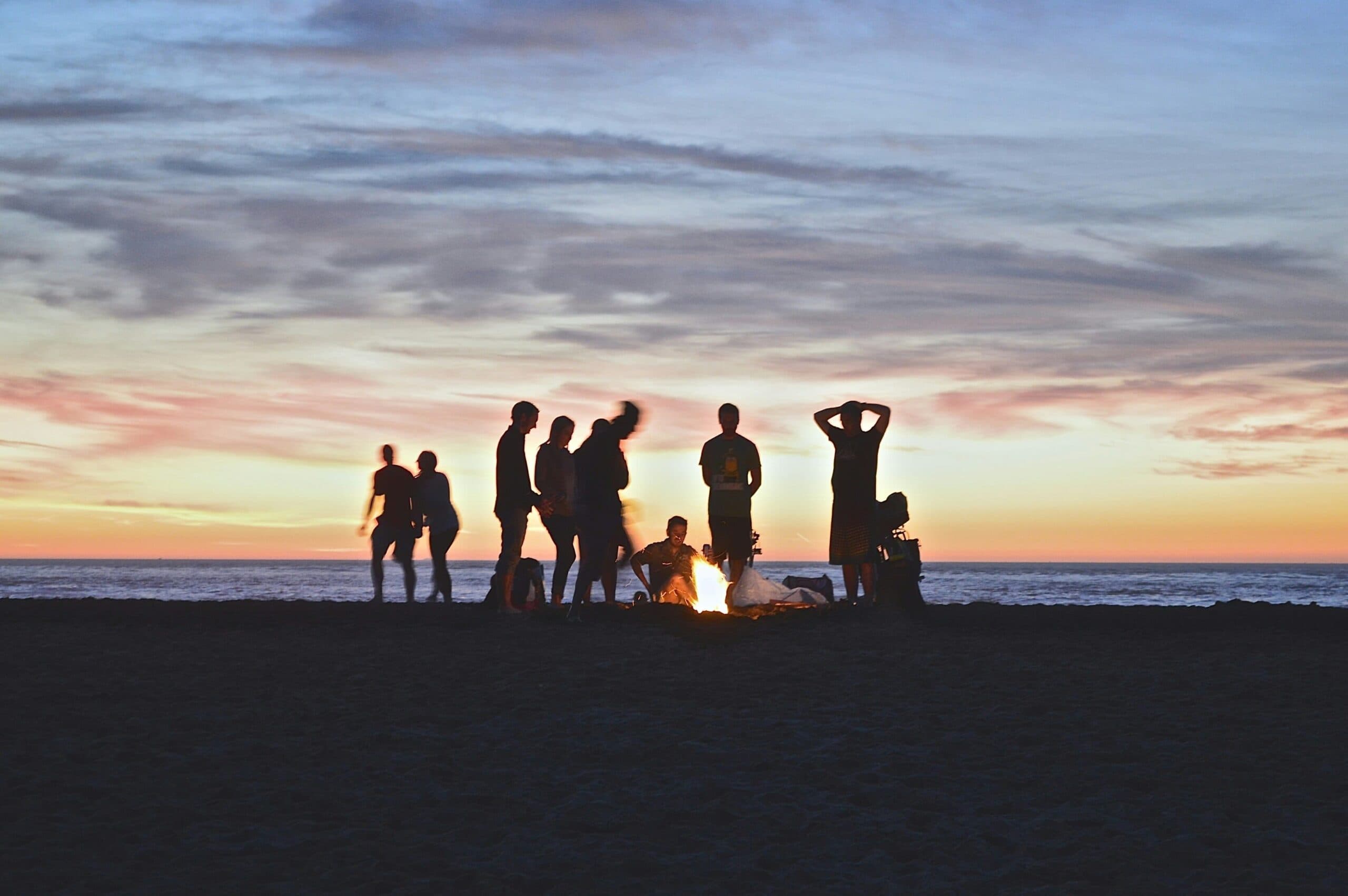 Friends gather around a beach bonfire