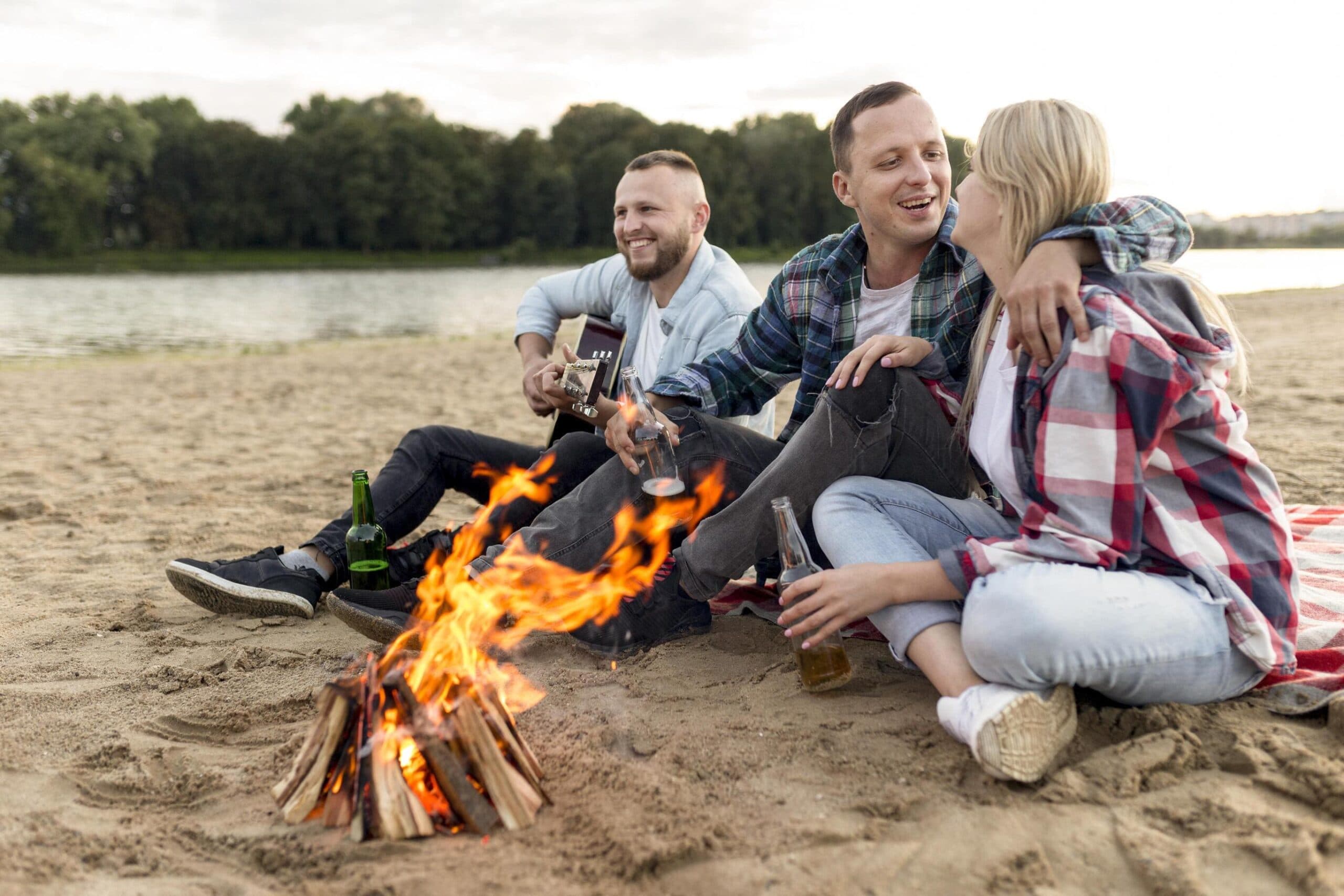 Friends play guitar and laugh by a campfire