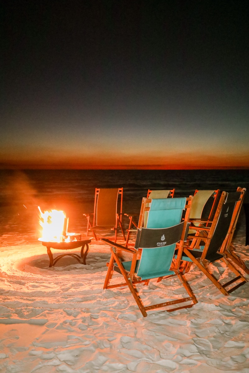 Corporate team gathered around beach bonfire